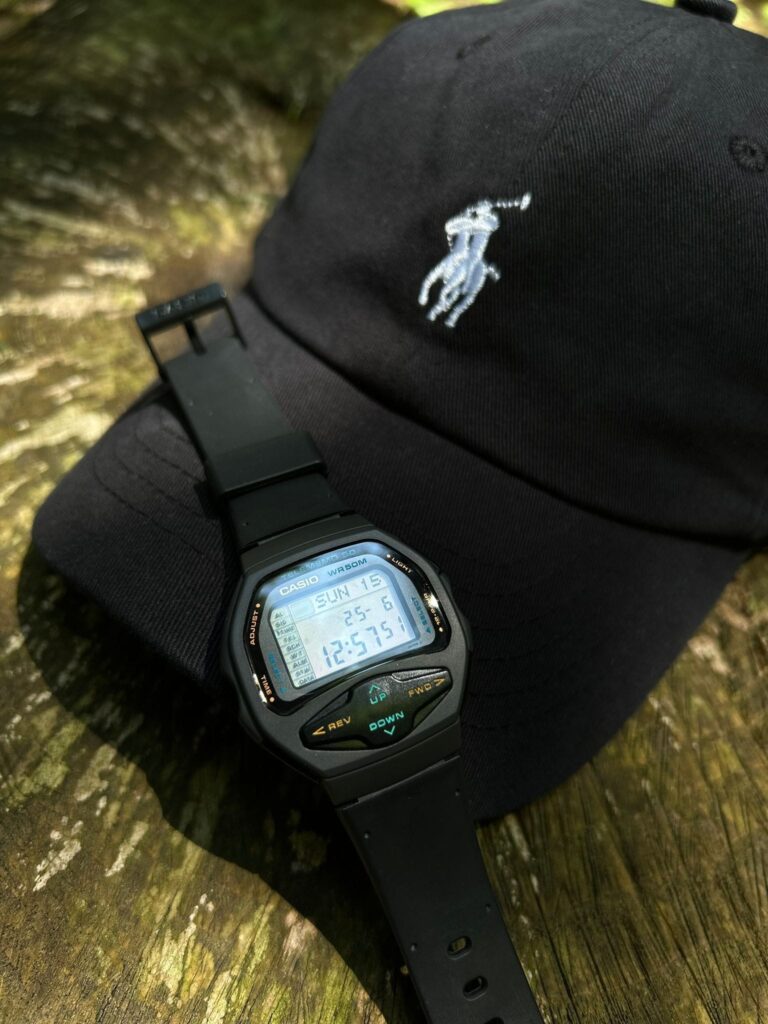Casio Databank watch on a black Polo cap outdoors.