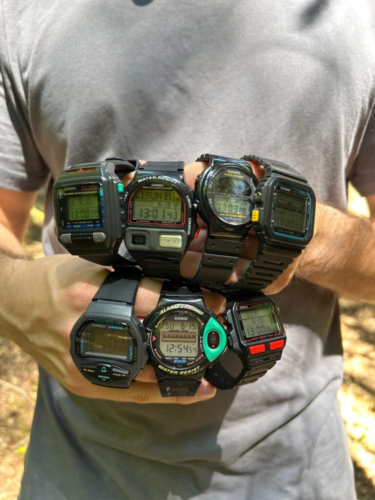 Collector holding six vintage Casio digital watches across both wrists.