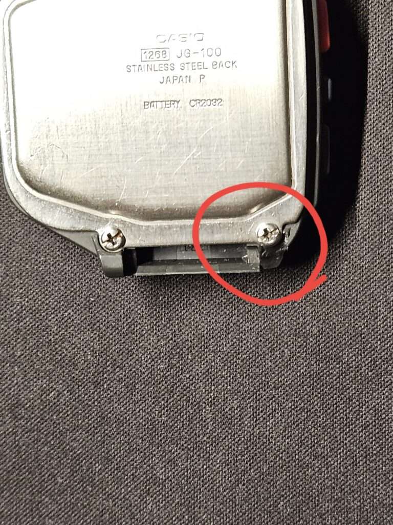 Casio JG-100 back case with visible plastic crack near strap mount.