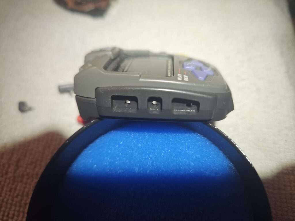 Close-up of the Casio JG-100 watch case showing the left-side button openings.