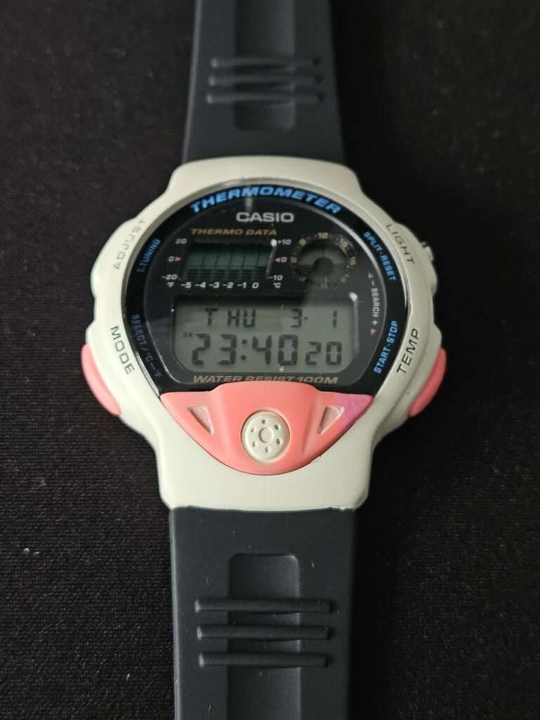 Restored Casio TS-200 digital thermometer watch front view with white case, pink accents and black rubber strap