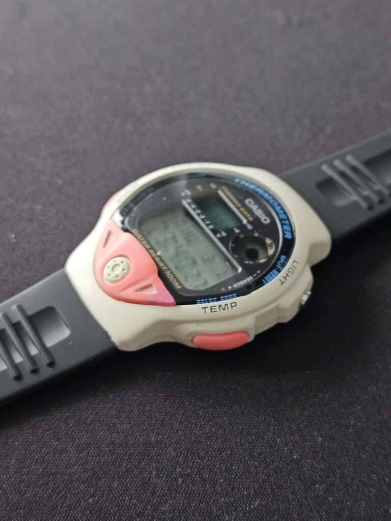 Casio TS-200 restored watch angled side view showing white case, pink TEMP button and black rubber strap
