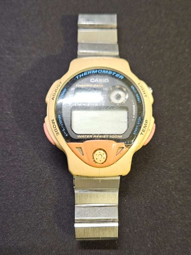 Casio TS-200 Thermometer digital watch before restoration, yellowed case with stainless steel bracelet on dark background