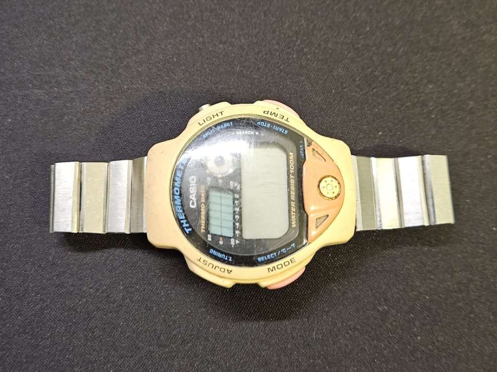 Casio TS-200 digital thermometer watch front view upside down, yellowed case with steel bracelet and active LCD display before restoration
