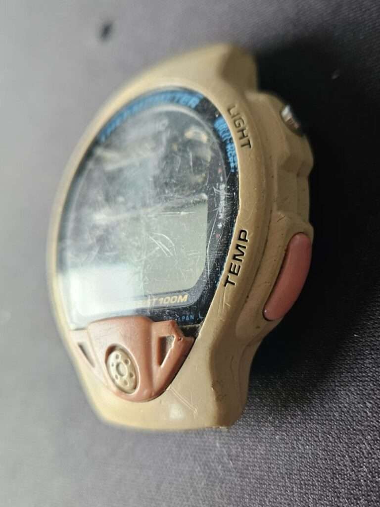 Casio TS-200 watch case side view showing yellowed plastic and scratched crystal during disassembly