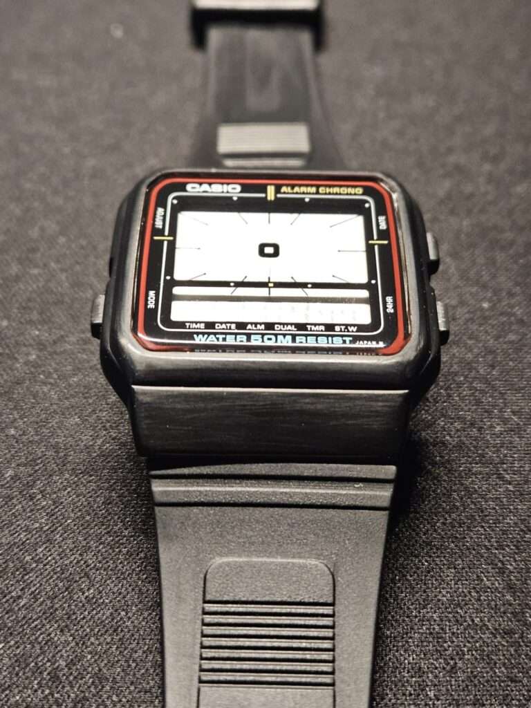 Restored Casio AE-11W Alarm Chrono angled front view with clear crystal and red bezel trim after restoration