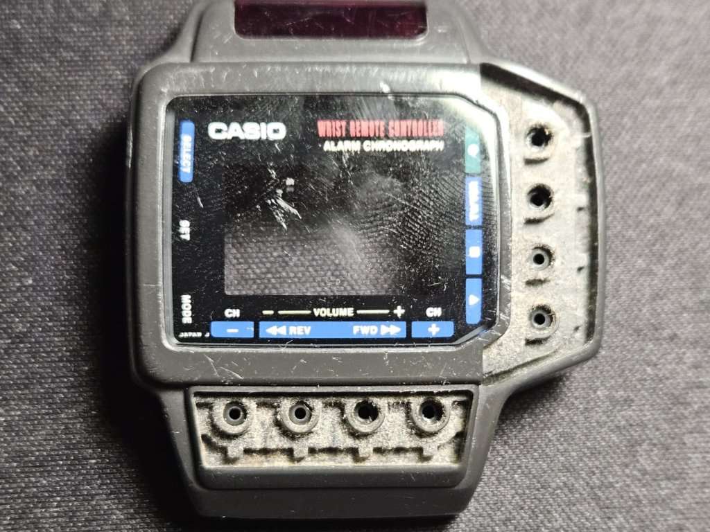 Casio CMD-10 wrist remote controller partially disassembled during restoration, missing buttons and cracked LCD lens visible