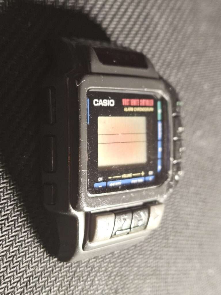 Casio CMD-10 wrist remote controller alarm chronograph tilted side angle view before restoration on gray fabric surface
