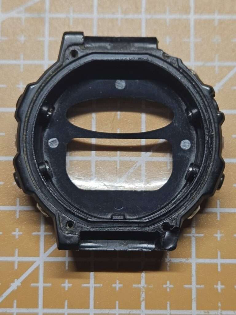 Casio CGW-50 Cosmo Phase black resin bezel inner frame disassembled, viewed from the back on a cutting mat