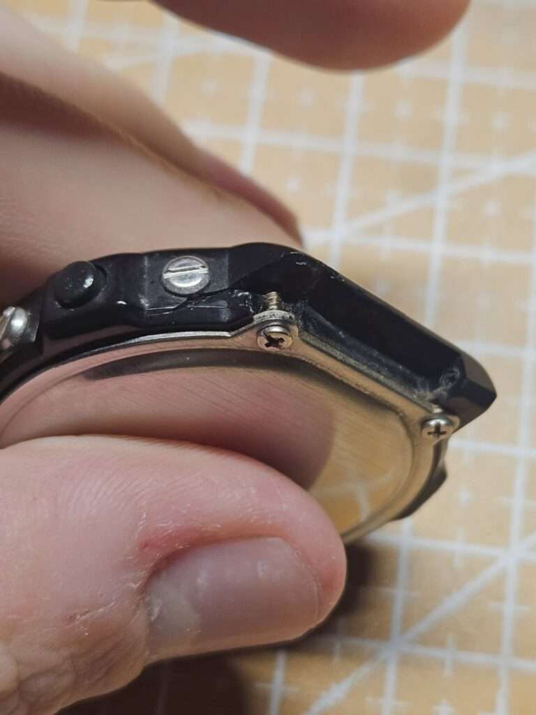 Casio CGW-50 Cosmo Phase side view showing broken lug, loose screws, and cracked black resin case