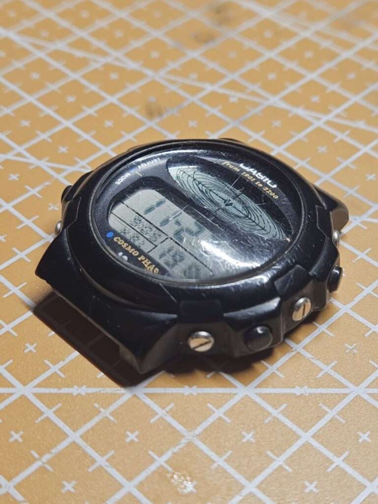 Casio CGW-50 Cosmo Phase front view with heavily scratched acrylic crystal and LCD dial before restoration