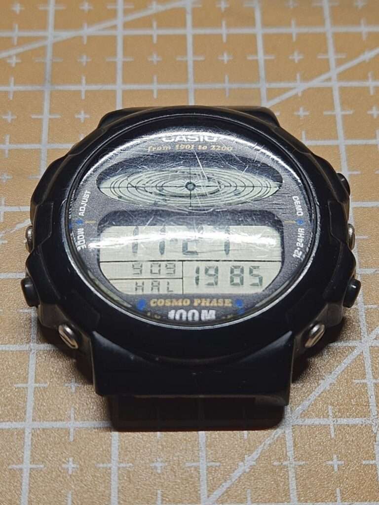 Casio CGW-50 Cosmo Phase angled side view with scratched crystal, black resin case, side buttons before restoration