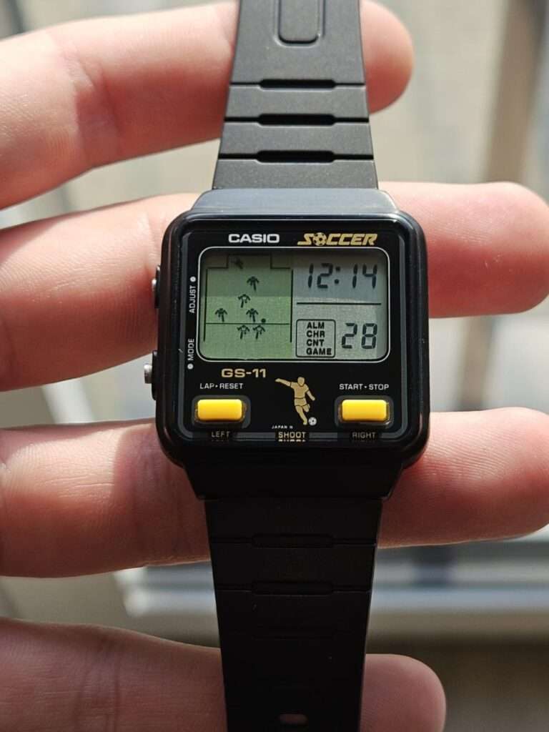 Restored Casio GS-11 Soccer watch angled side view with black bracelet and clear LCD showing soccer gameplay