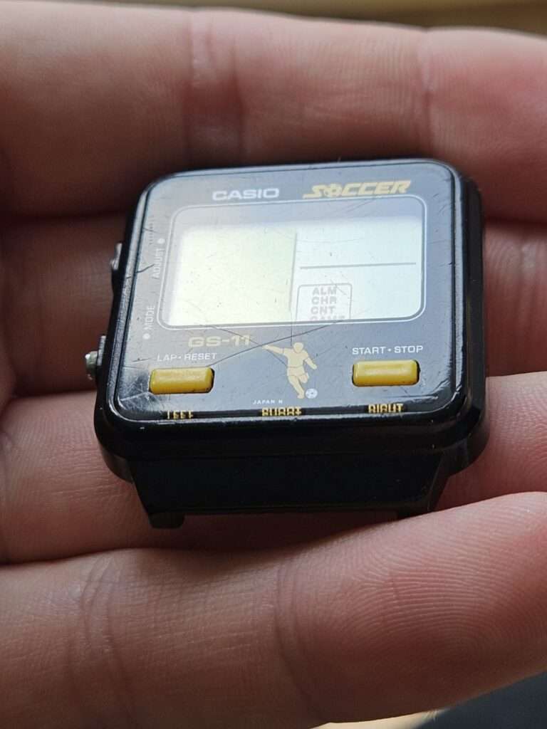 Casio GS-11 Soccer game watch angled side view showing thick black case and scratched LCD, unrestored