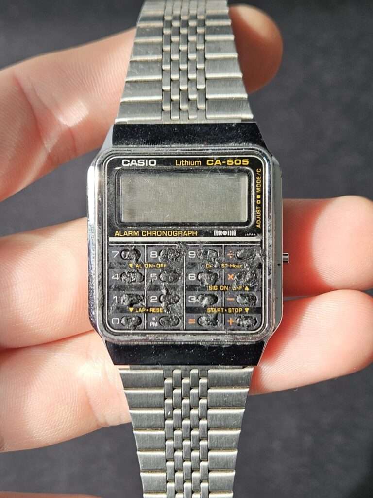 Casio CA-505 calculator watch before restoration showing heavily degraded keys and dirty dial held in hand