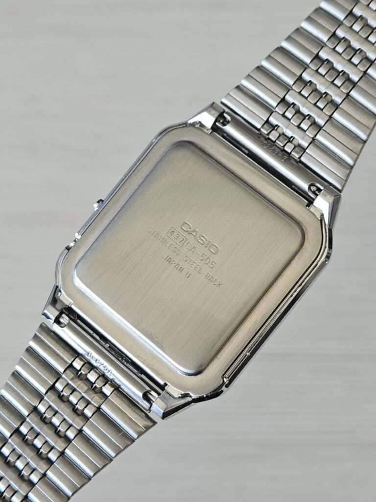 Casio CA-505 stainless steel back cover after restoration with engraving and restored natural brushed finish