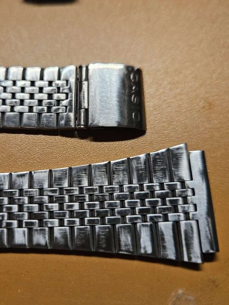 Casio CA-505 stainless steel bracelet during scratch removal process showing before and after sanding results