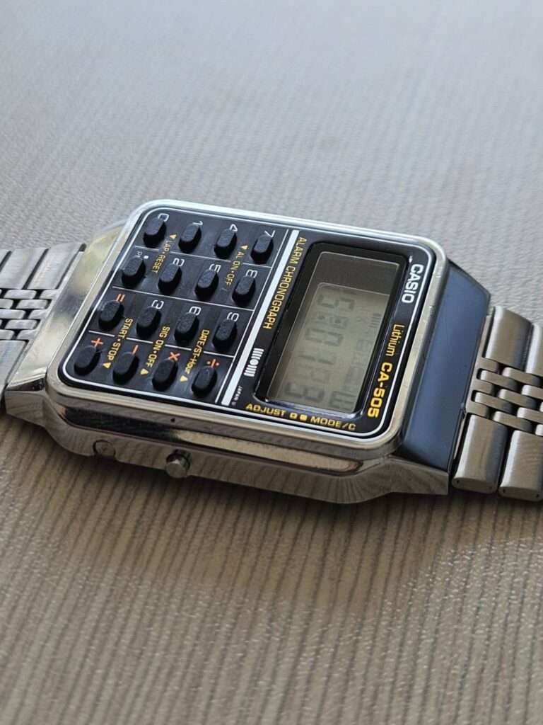 Restored Casio CA-505 calculator watch angled side view showing polished stainless steel case and bracelet
