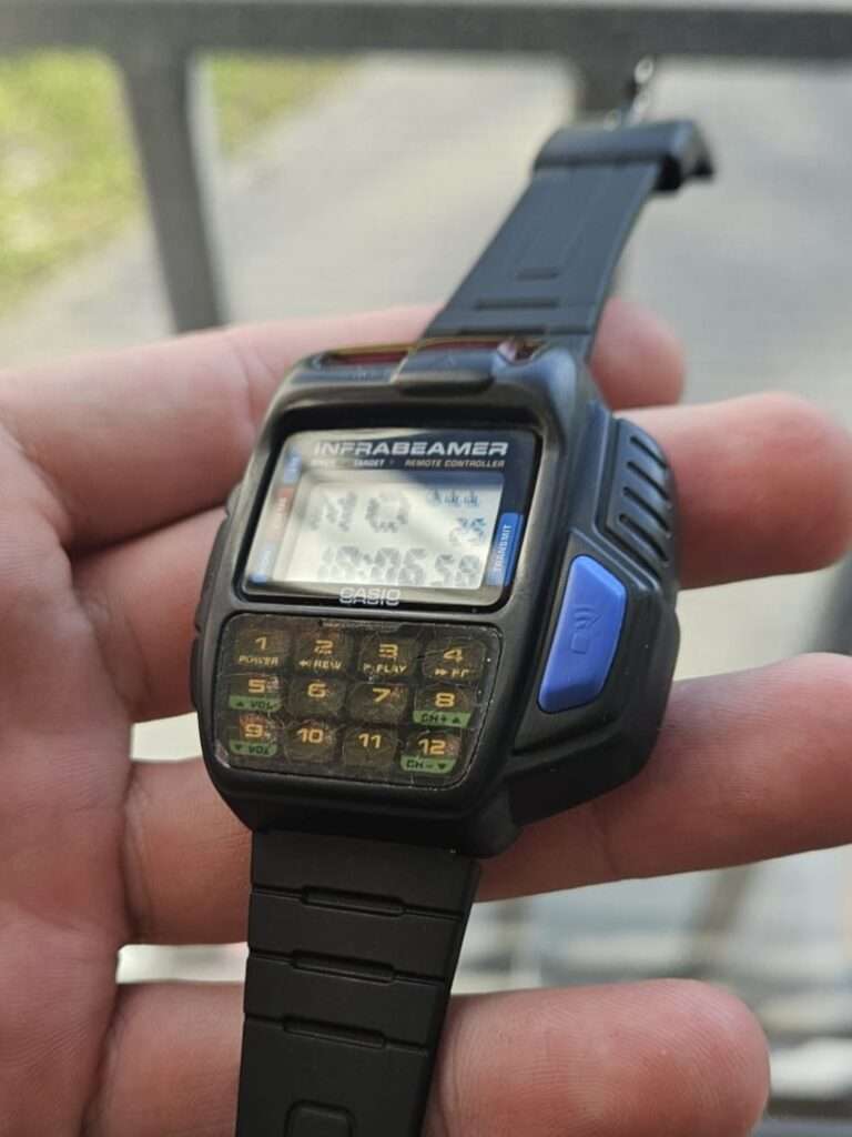 Casio JG-10 Infrabeamer watch held in hand outdoors showing working LCD and 12-button keypad after restoration