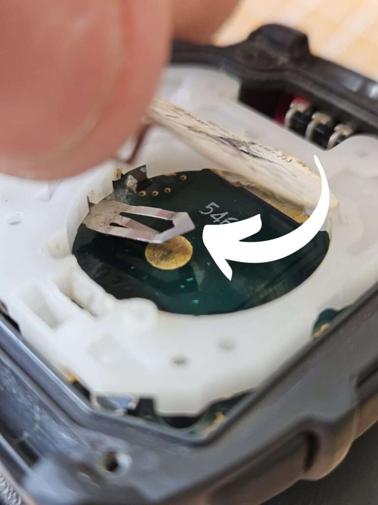 Casio JG-10 watch open during restoration showing newly added metal battery clip fitted into battery compartment on PCB