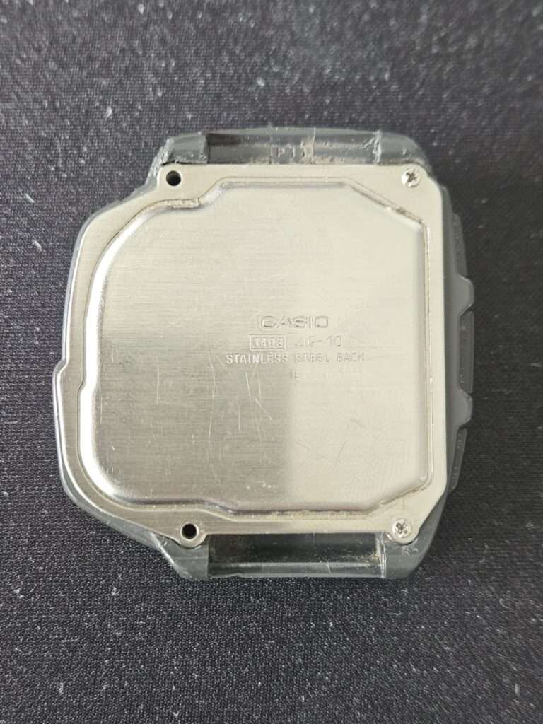 Casio JG-10 stainless steel case back engraved with module number 1403 showing scratches before restoration