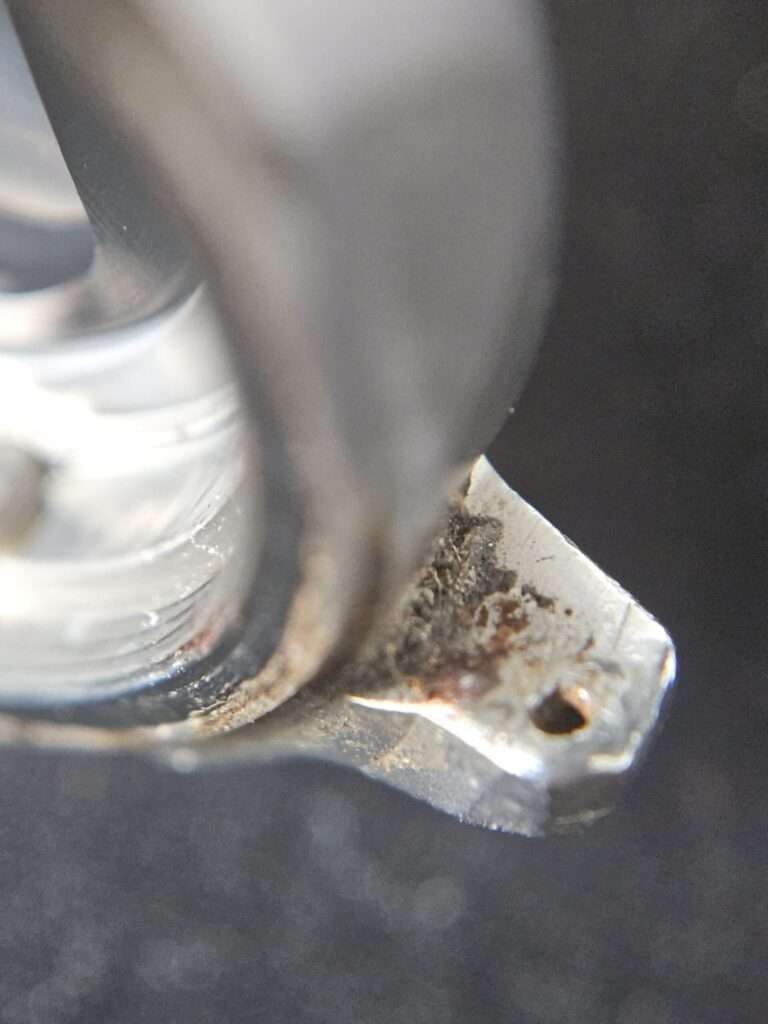 Macro of Casio CGW-500 Cosmo Phase steel case corner showing dirt, rust spots and a screw hole before cleaning