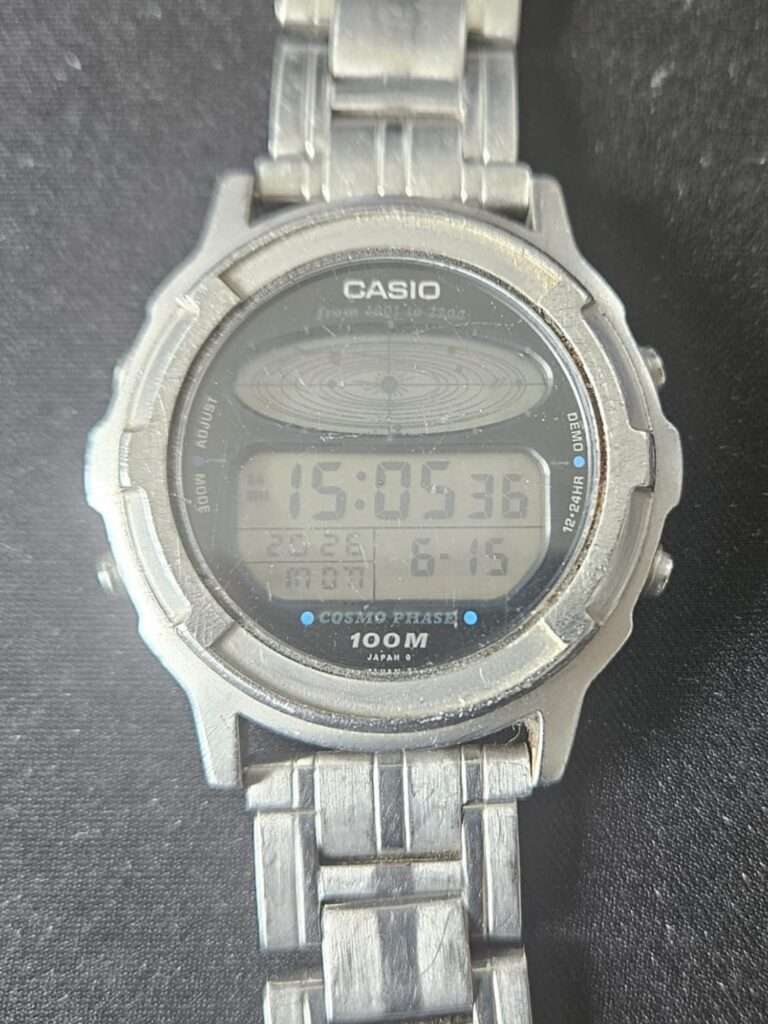 Casio CGW-500 Cosmo Phase digital watch on black background showing 100M case and steel bracelet before restoration