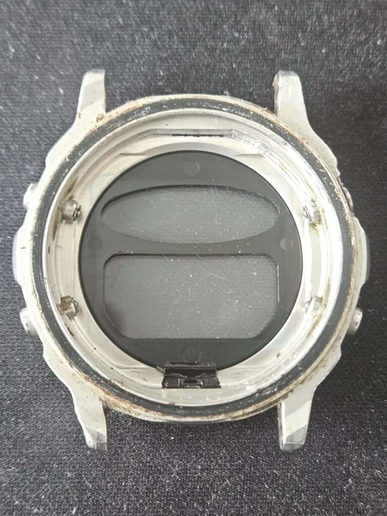 Empty Casio CGW-500 Cosmo Phase steel case interior with crystal removed, showing dust and corrosion before cleaning
