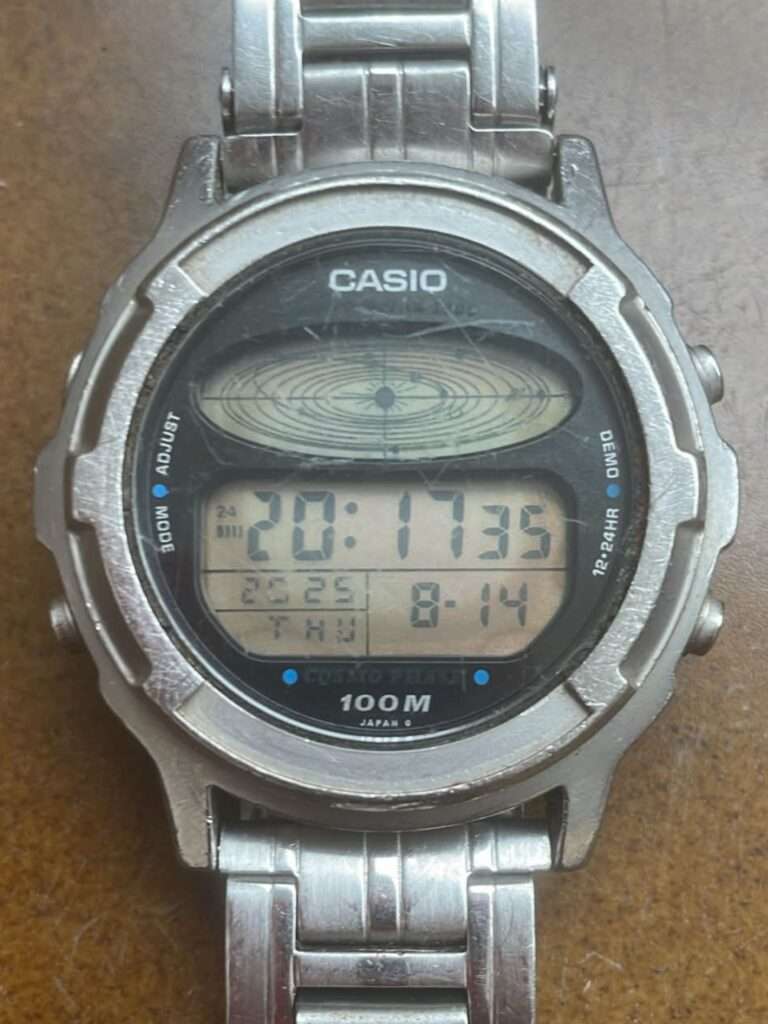 Casio CGW-500 Cosmo Phase digital watch on brown surface, worn case and faded display before restoration