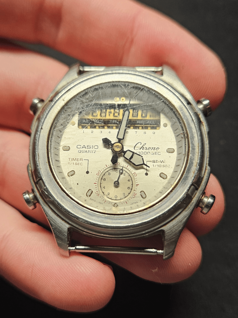 Casio AW-600 dial with severely cracked crystal and worn hands before restoration