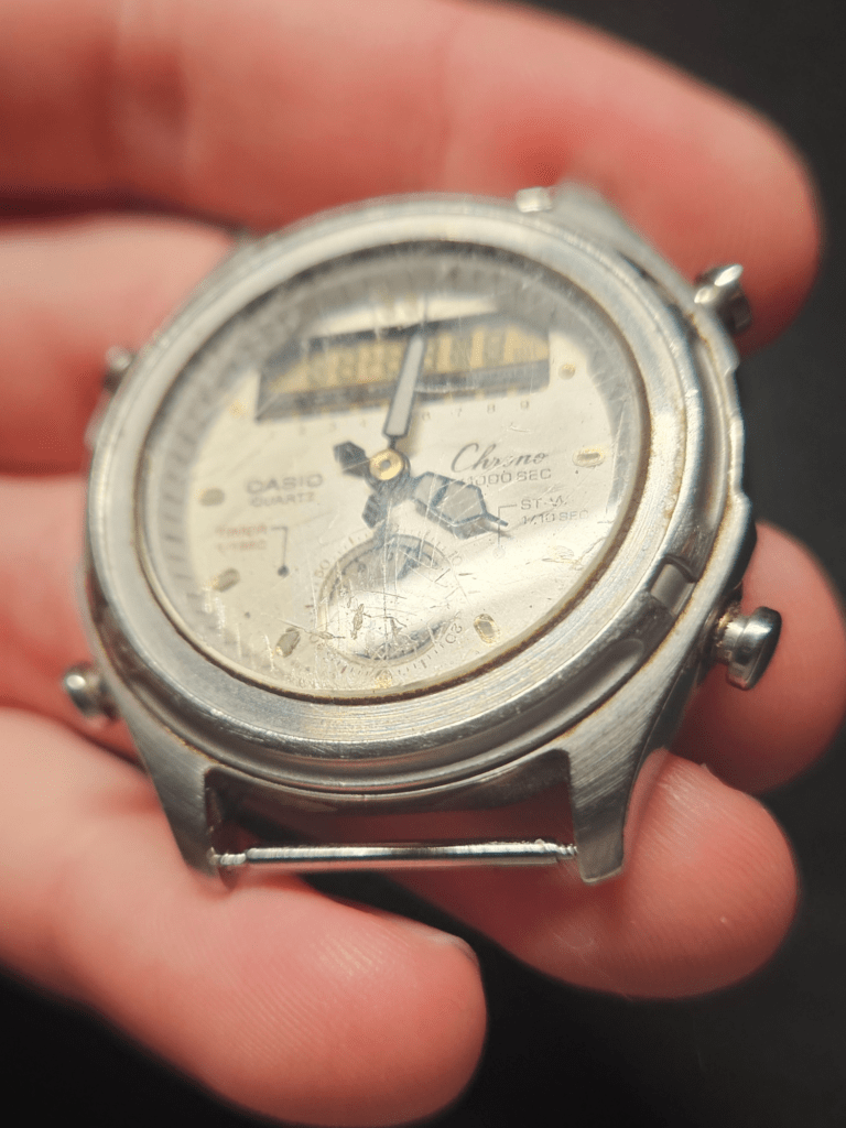 Close-up of worn Casio AW-600 dial and scratched crystal before restoration