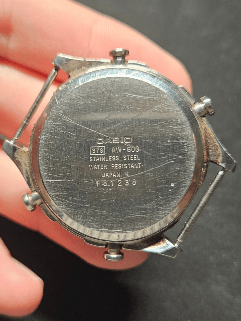 Heavily scratched Casio AW-600 caseback before restoration showing model markings