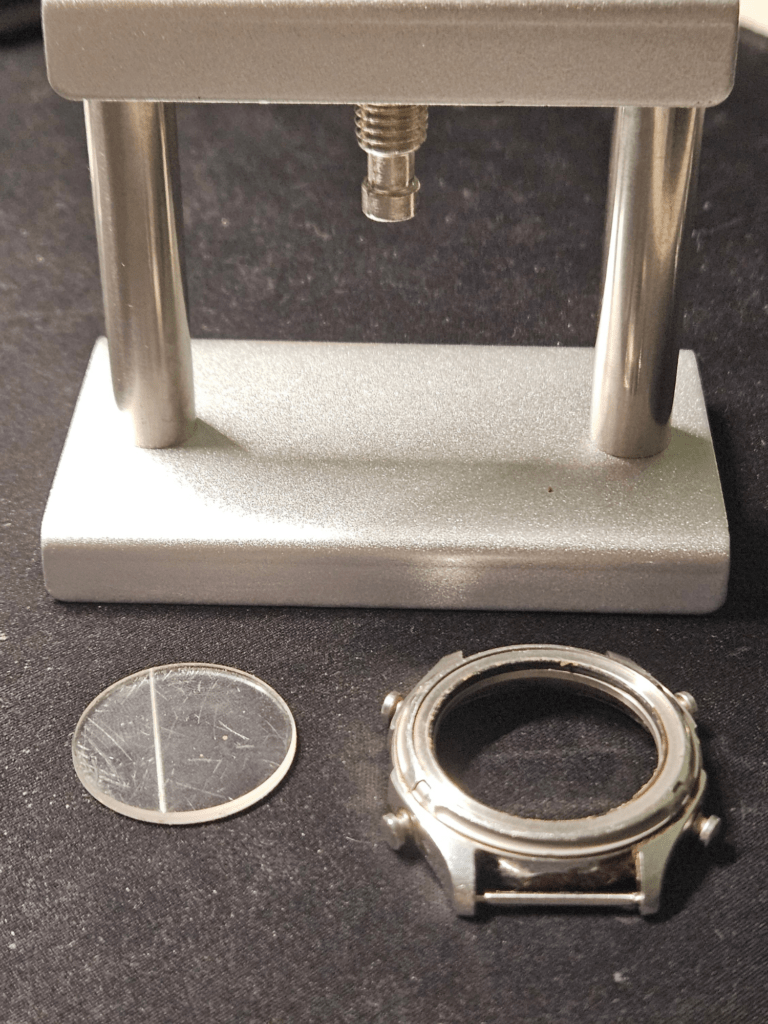 Casio AW-600 watch crystal removed from case using a press tool during restoration